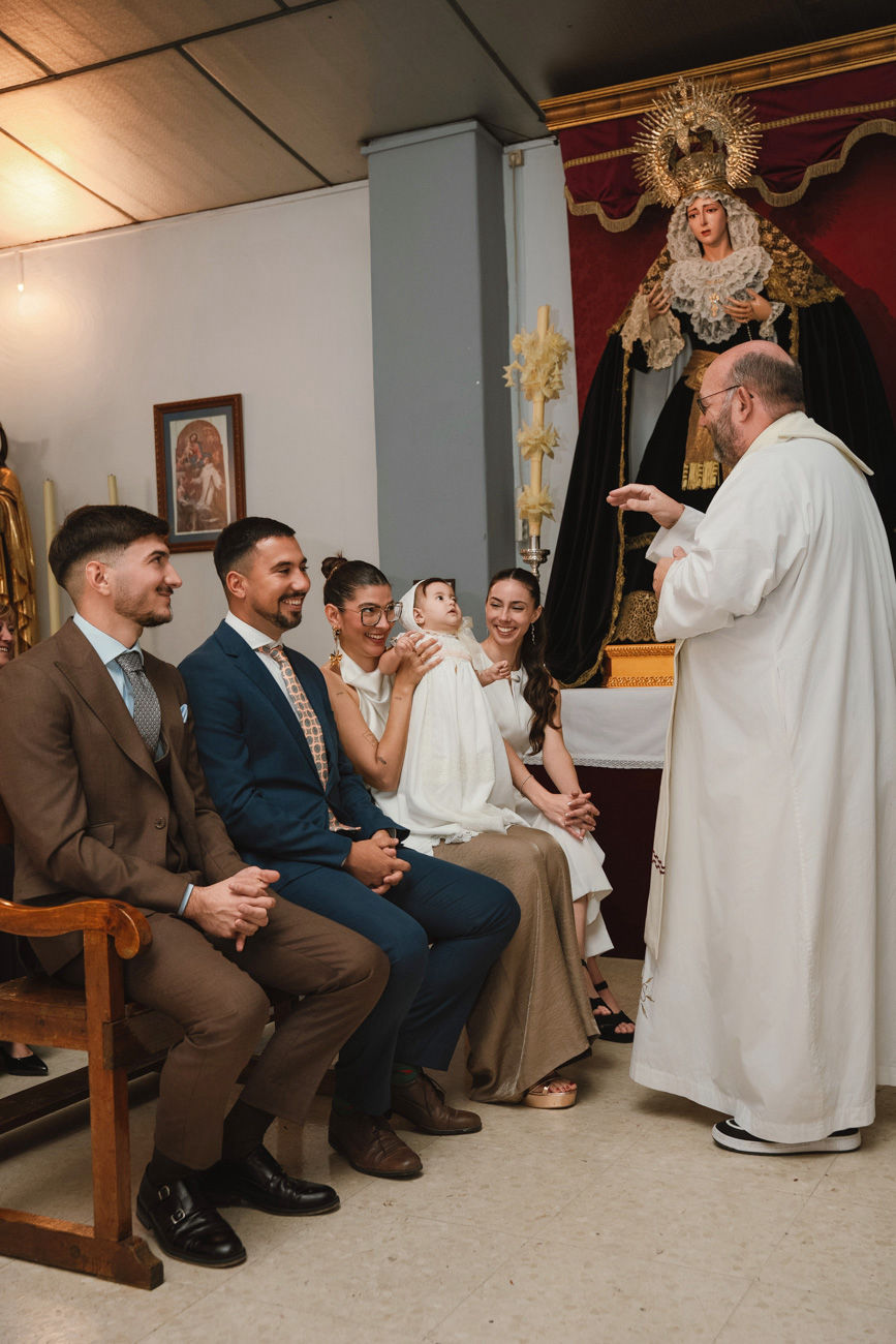 bebé en brazos de la madrina durante su bautizo en la iglesia de san román sevilla fotografía profesional de foto eventos
