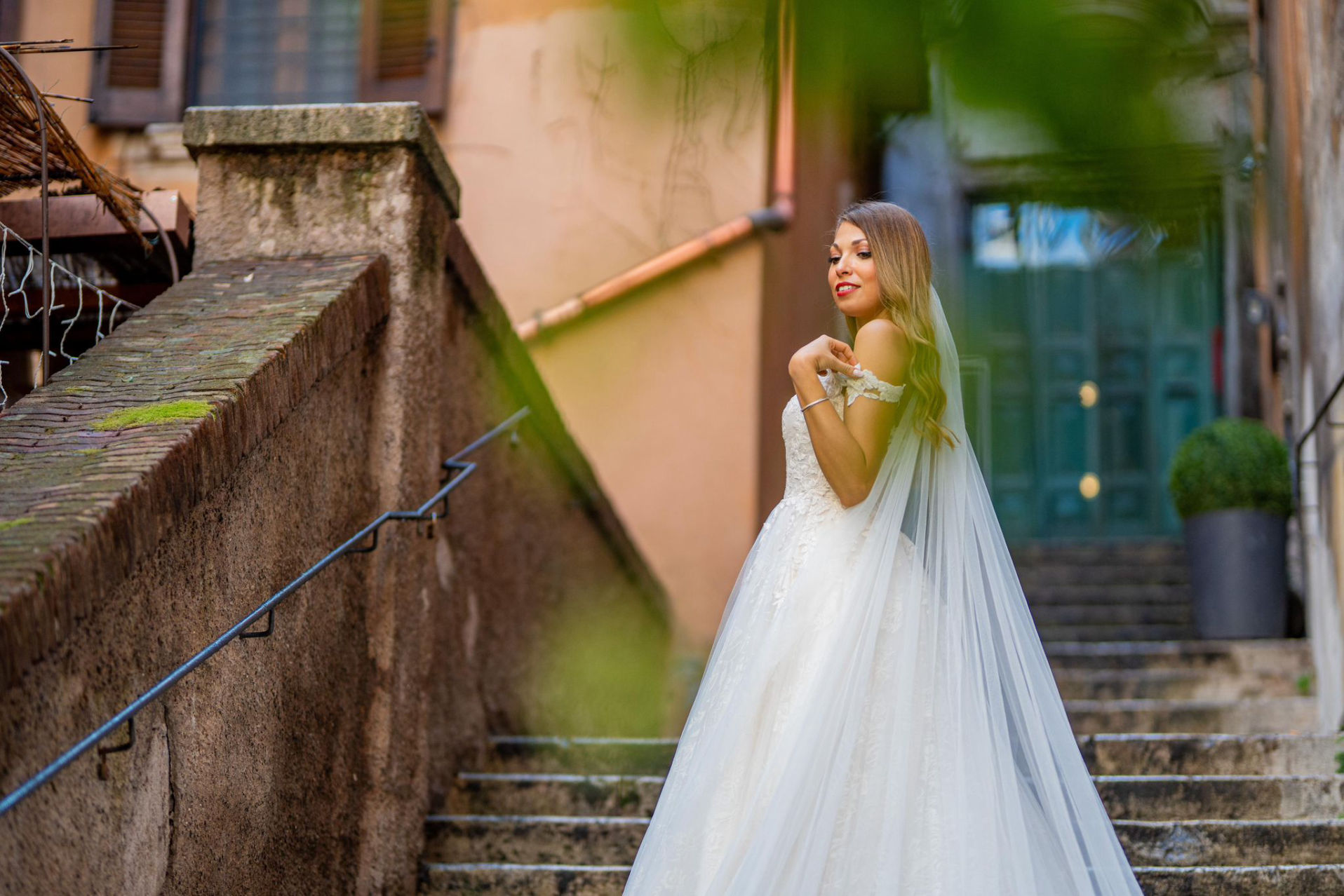 Novios en Piazza San Salvatore, Roma, posando en una escalera con reflejo en el suelo mojado.